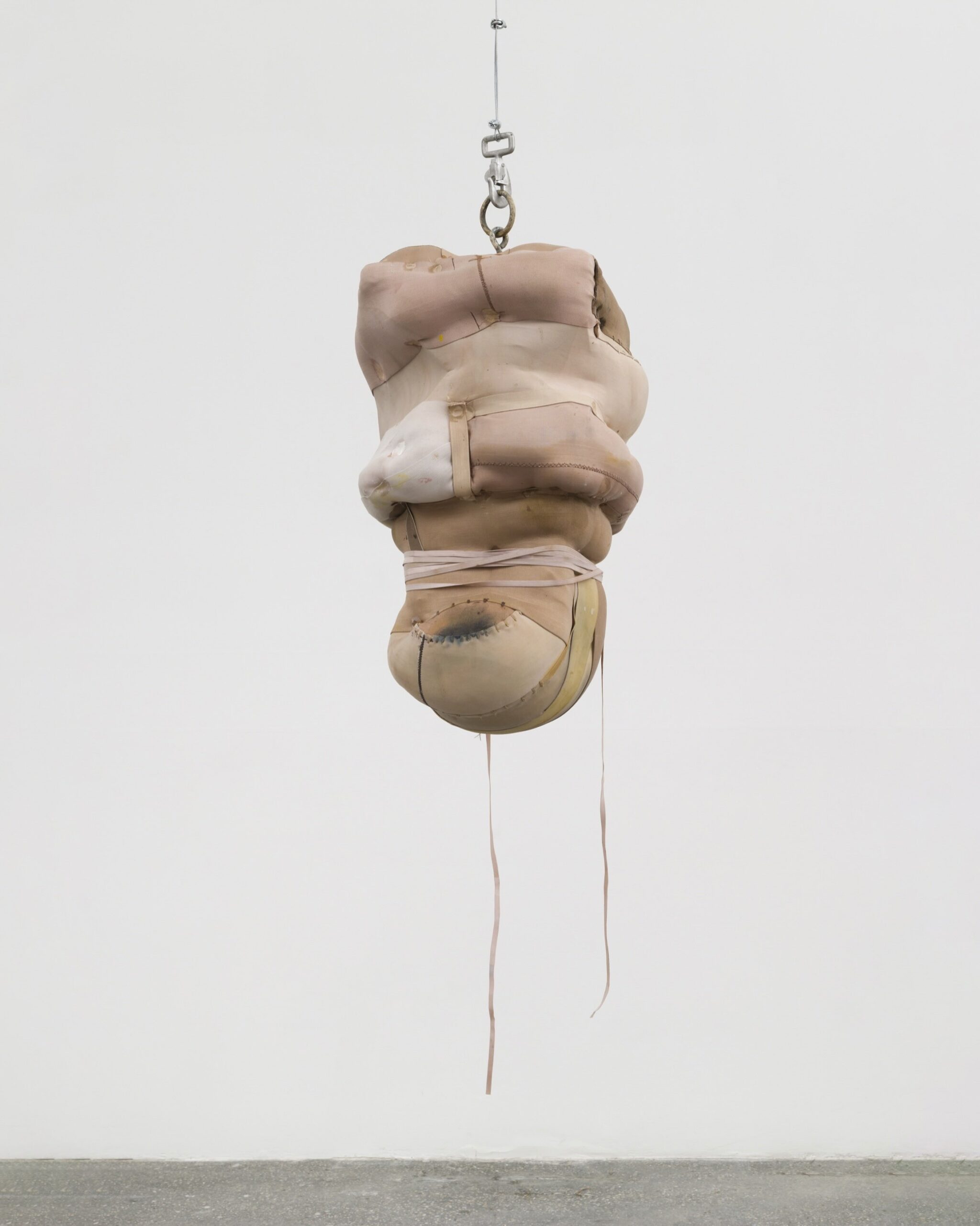 Patricia Ayers, a part of « Tightrope » at Bradley Ertaskiran, in collaboration with Matthew Brown Gallery. A suspended work of fabric mimicking human form is constricted within its own being.